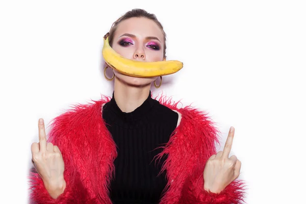 Frau im rosafarbenen Pelzmantel macht sich über Banane lustig — Stockfoto