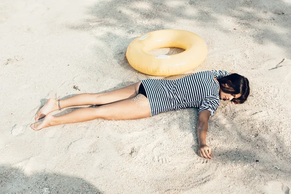 Young female model lying on the beach, sunbathing and relaxing — Stok fotoğraf