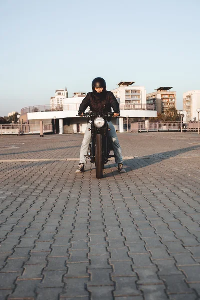 Motorbiker sitter på cykel på parkeringsplats i staden — Stockfoto