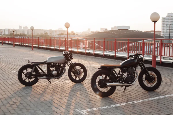 Two vintage motorcycle in parking lot during sunset