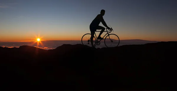 The silhouette of the cyclist on bike at sunset.A man ride on bike on the mountains. Sport and active life concept sunset time. A man riding on bicycle in a nature.