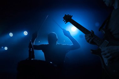 Konser sırasında canlı performans, konser. Gitarist ve davulcu siluetleri
