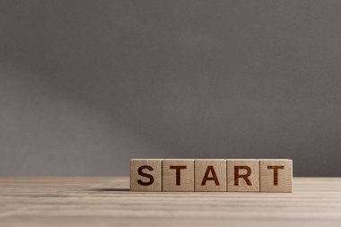 Güzel bir ahşap masada 'START' kısaltmalı tahta küpleri, stüdyo arka planı. Kopyalama alanı ile iş kavramı.