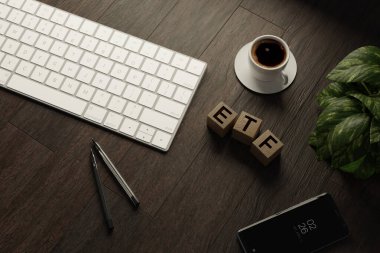 Evden çalışıyorum. Klavyeli masa ofisi, ETF tahta küpleri, sehpanın üzerinde kahve fincanı ve kalem. Düz üst görünüm