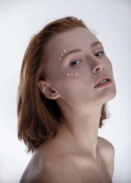 Yüzünde makyaj malzemesi olan gülümseyen bir kız.