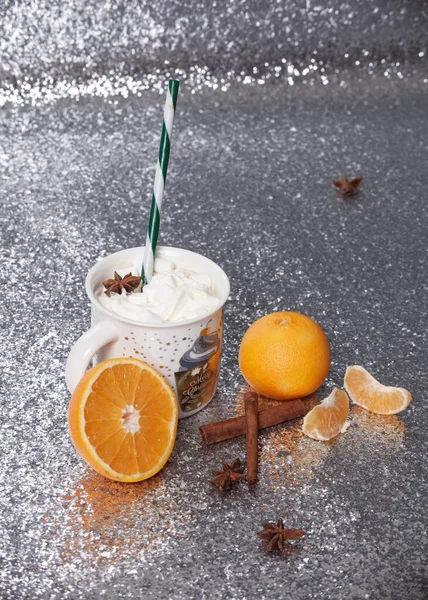 christmas cocoa with oranges and cinnamon on silver background