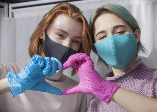 Maske takıp parlayan iki mutlu kız.