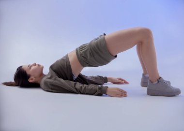 Renkli spor kıyafetleri içinde güzel bir kız parlak bir odada bir halter tutuyor.