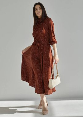 Renkli bir bahar elbisesi içinde, açık bir arka planda güzel bir kız.