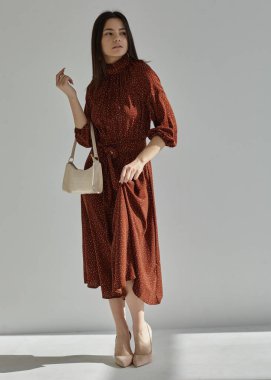 Renkli bir bahar elbisesi içinde, açık bir arka planda güzel bir kız.