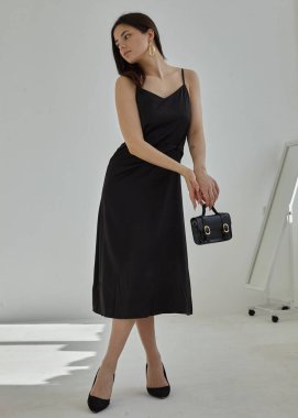 İpek bir bahar elbisesi içinde açık renk bir arka planda siyah bir esmer.