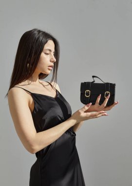 Siyah ipek bir bahar elbisesi içinde, açık arkaplanda güzel bir esmerin portresi.