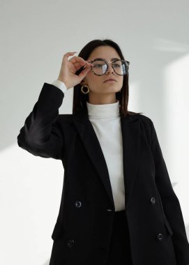 Güzel bir esmerin portresi şık bir ofis elbisesi içinde açık bir arka planda.