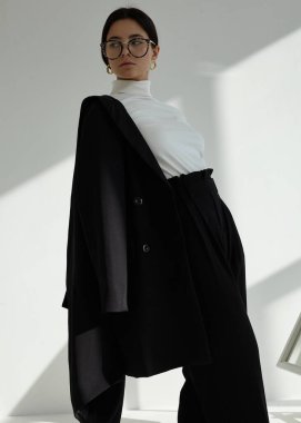 Güzel esmer, şık bir ofis elbisesi ve açık bir arka planı var.