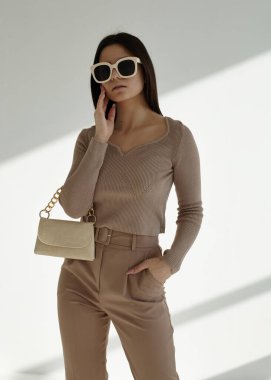 Güzel bir esmerin portresi şık bir bahar elbisesi içinde, gözlüklü ve çantalı.