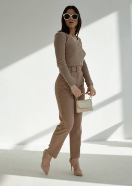 Şık bir bahar elbisesi içinde, gözlüklü ve poz veren güzel bir esmer.