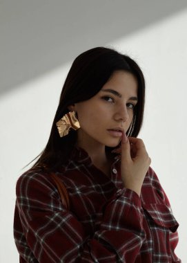 Açık arkaplanda kırmızı ekose gömlekli güzel bir esmerin portresi.