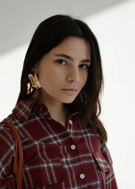 Açık arkaplanda kırmızı ekose gömlekli güzel bir esmerin portresi.