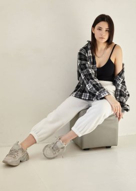 Güzel esmer, ekose gömlekli, boynunda mücevherlerle.