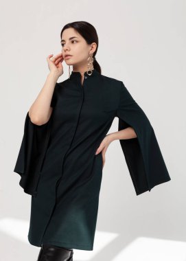 Güzel esmer, şık bir bahar elbisesi içinde, yırtık kolları ve yüksek siyah çizmeleri var.