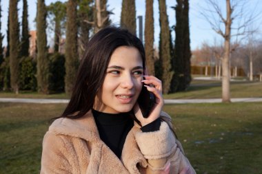 Parkta güzel bir esmer telefonda duygusal konuşuyor.