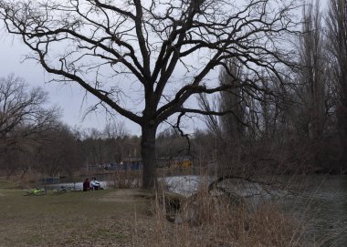 İnsanlar parkta nehrin kenarında dinleniyorlar.