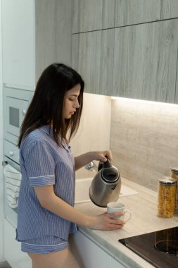 Güzel esmer kendine çay yapıyor.