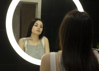 beautiful brunette applying morning makeup at home
