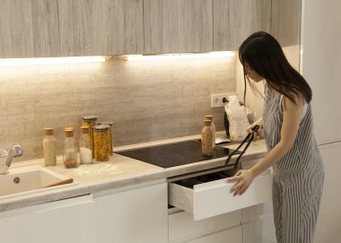 beautiful brunette in the kitchen opens the wardrobe