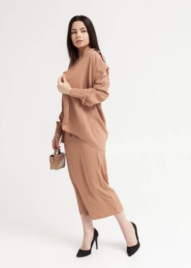 Kahverengi bir yaz elbisesi içinde elinde bir çantayla güzel bir esmer.