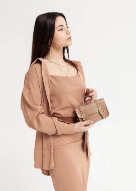 Kahverengi bir yaz elbisesi içinde elinde bir çantayla güzel bir esmer.