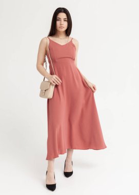 Güzel esmer, uzun, pembe bir elbise ve beyaz bir çanta.