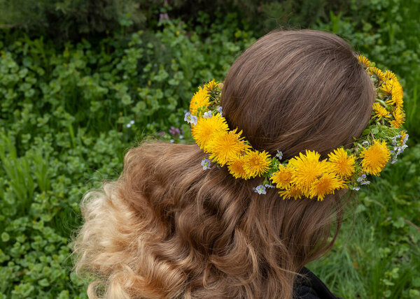 a wreath of yellow dandelions on a girl with long hair