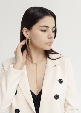 Büyük küpeleri olan beyaz ceketli güzel bir esmerin portresi.