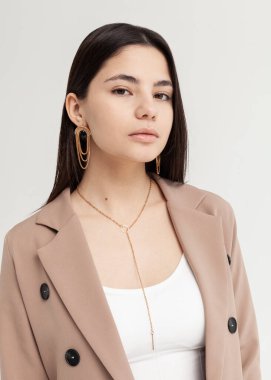 Kahverengi ceketli, kocaman küpeli güzel bir esmerin portresi.