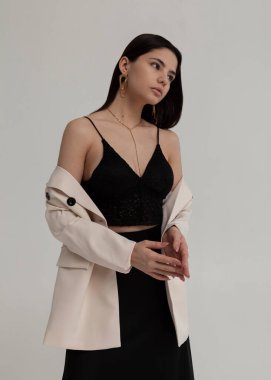 Siyah elbisesi ve beyaz ceketi olan güzel bir esmer.