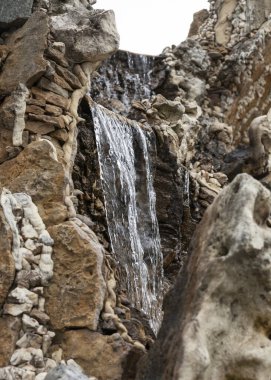 Çeşmede bir şelaleyle taşlardan aşağı su akar.