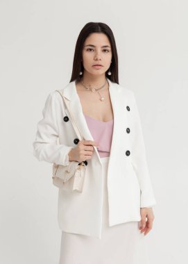 Beyaz takım elbiseli, elinde bir çantayla güzel bir esmer.