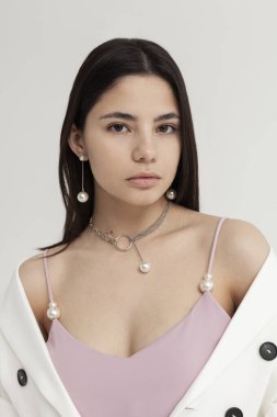 Beyaz ceketli ve küpeli güzel bir esmerin portresi.