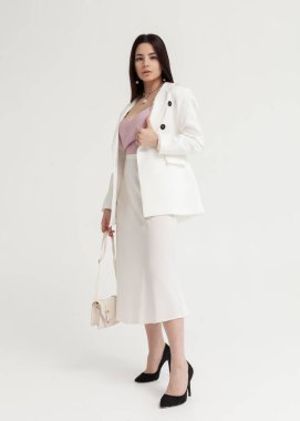 Beyaz bir yaz elbisesi içinde açık renk bir arka planda güzel esmer.