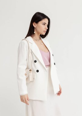 Beyaz takım elbiseli, elinde bir çantayla güzel bir esmer.