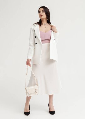 Beyaz bir yaz elbisesi içinde açık renk bir arka planda güzel esmer.