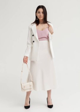 Beyaz bir yaz elbisesi içinde açık renk bir arka planda güzel esmer.