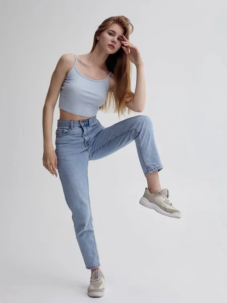 Uzun saçlı güzel bir kız yaz kıyafetleriyle arka planda poz veriyor.