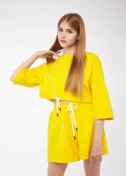 Beyaz arka planda sarı takım elbiseli güzel bir kızın portresi.