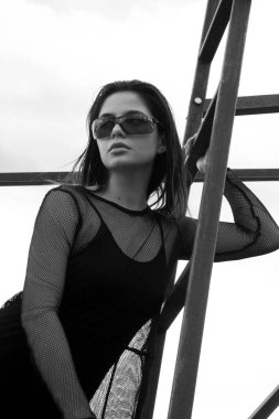 Siyah elbiseli, merdivenlerde güneş gözlüklü güzel bir esmer.