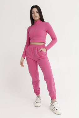 Açık arkaplanda pembe eşofmanlı güzel esmer.