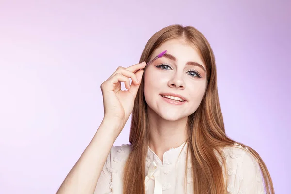 Güzel kızıl kız kaşlarını boyuyor.