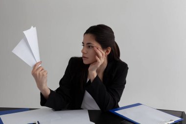 Güzel esmer, duygusal olarak ofiste kağıtlarla çalışıyor.