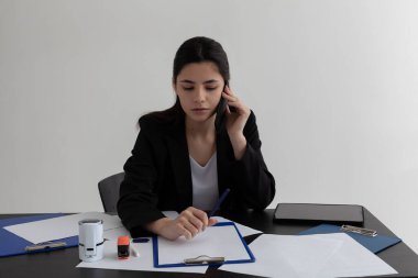 Güzel esmer, ofiste telefonla konuşuyor.